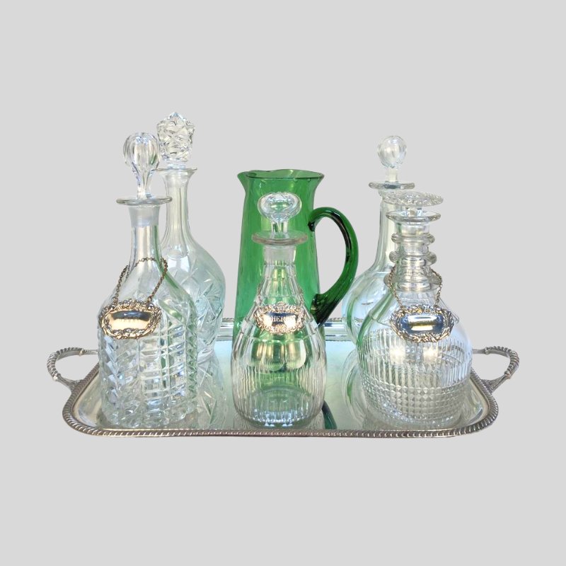 silver drinks tray with five decanters & a green glass jug